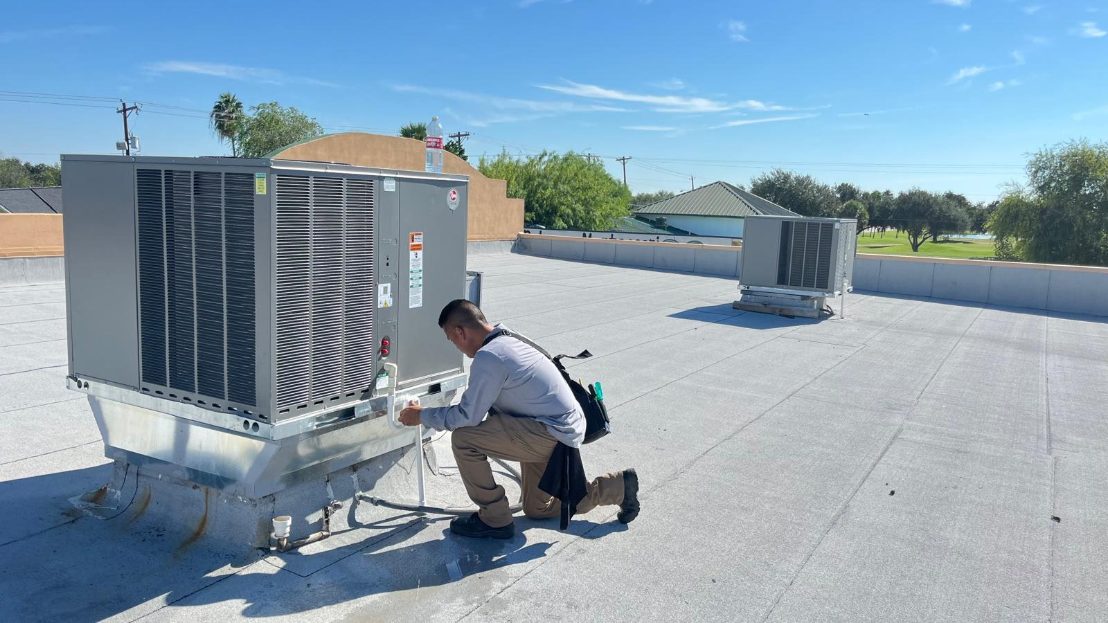 HVAC technician servicing a rooftop AC unit for a property in the Rio Grande Valley