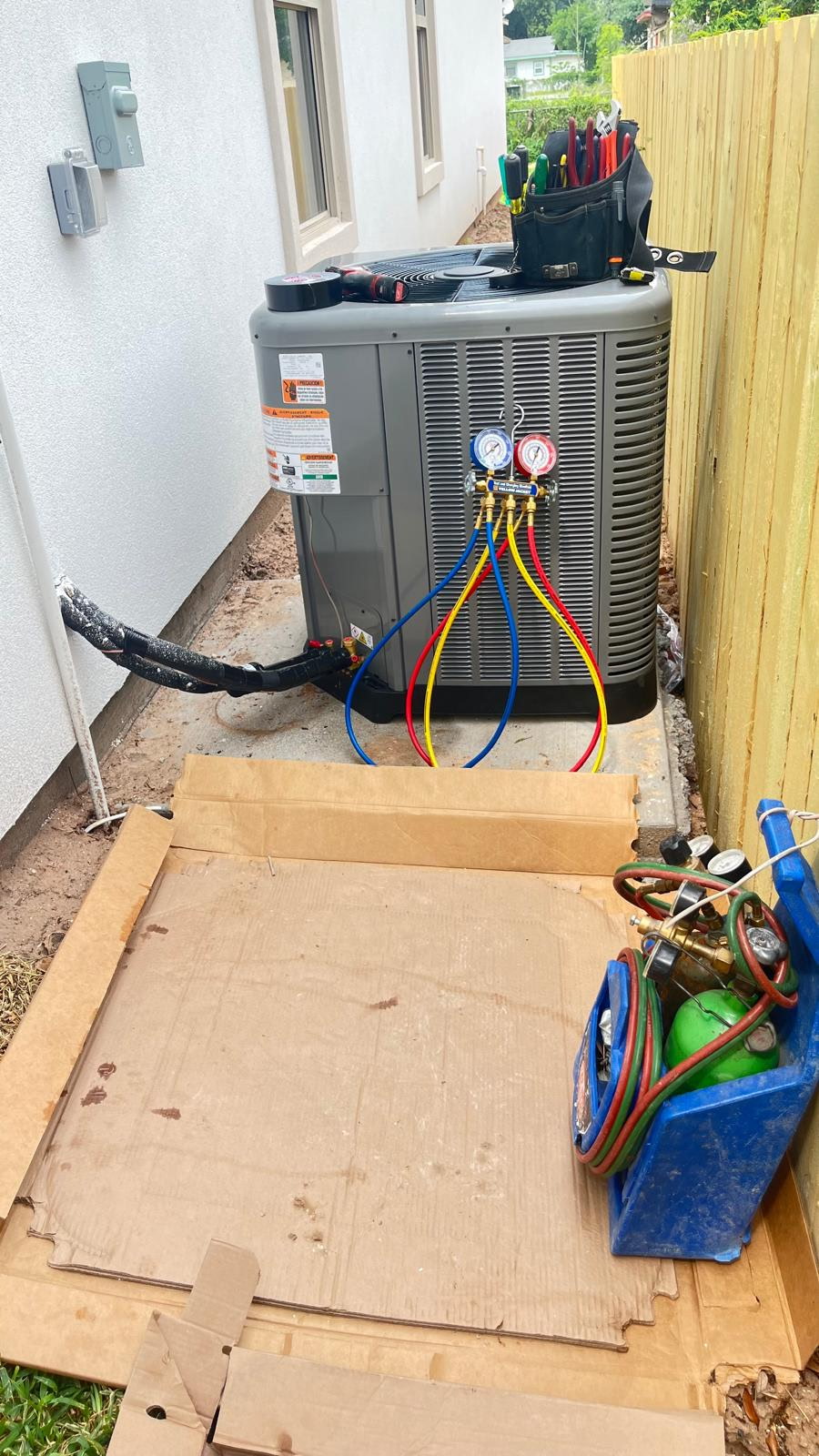 Climate Heating & Cooling refrigerant manifold gauges connected to a residential AC condenser during an air conditioning repair at a Mission, TX home